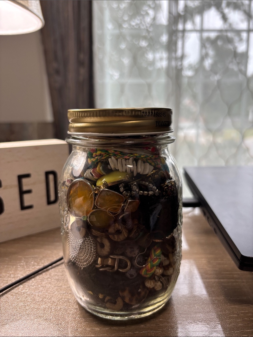Glass Mason Jar with Gold Lid filled with junk jewelry.  No wearable pcs.